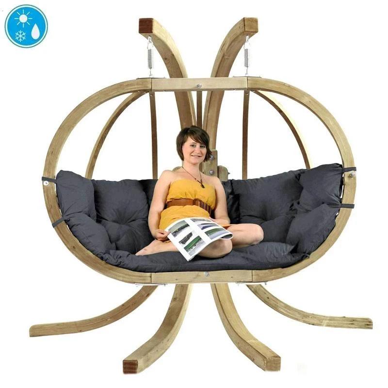 A person sitting on a Globo Royal Double Hanging Egg Chair set with a grey cushion, indoors.
