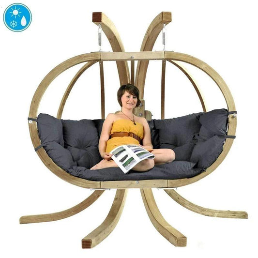 A person sitting on a Globo Royal Double Hanging Egg Chair set with a grey cushion, indoors.